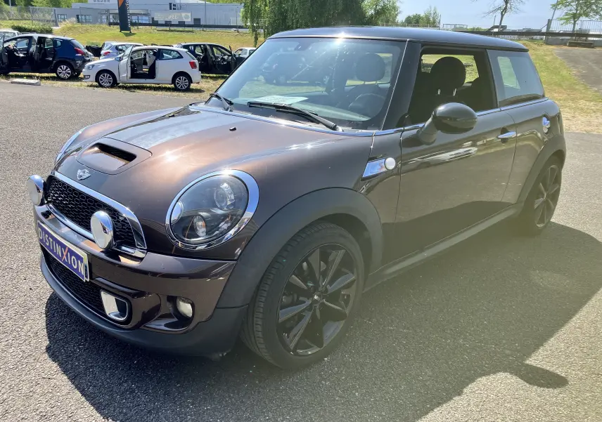 Vue 3/4 avant droite d'une MINI Cooper S R56 marron avec jantes noires et phares ronds chromés.