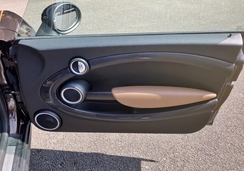 Vue de la porte côté gauche ouverte d'une MINI Cooper marron 2012, avec poignée beige et détails noirs.