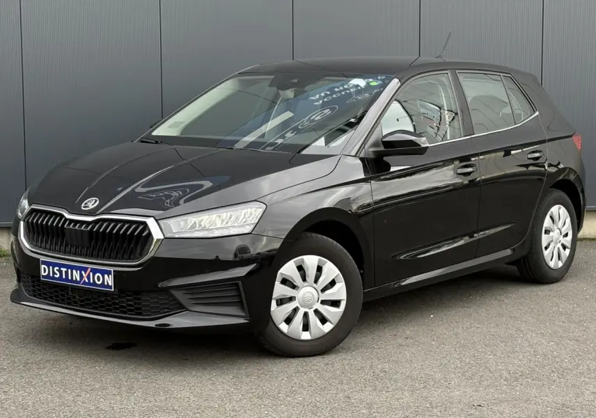 Vue 3/4 avant droite d’une SKODA FABIA 2024 noire Magic avec calandre chromée et jantes acier sur parking.