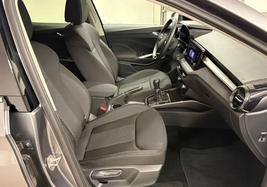Vue intérieure côté conducteur de la Skoda Fabia 2023 gris graphite, avec sièges tissu et boîte manuelle visible.