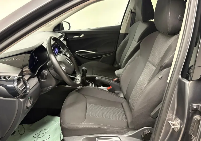 Vue intérieure côté conducteur de la Skoda Fabia 2023 gris graphite, montrant sièges, volant et tableau de bord moderne.