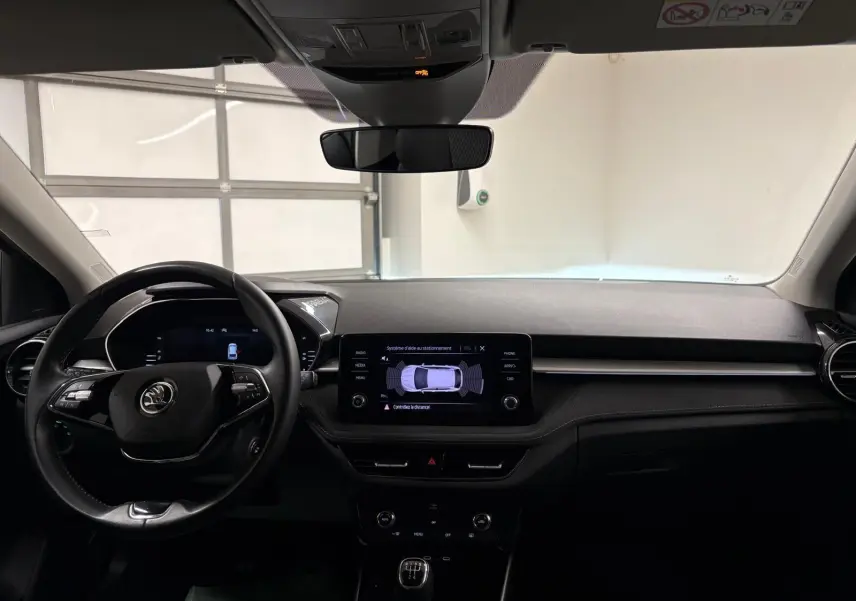 Intérieur de la Skoda Fabia 2023 gris graphite vu de face, tableau de bord avec écran tactile et volant multifonction.