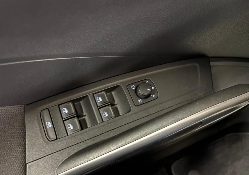 Gros plan sur la commande des vitres et rétroviseurs côté conducteur de la Skoda Fabia 2023 en intérieur noir.