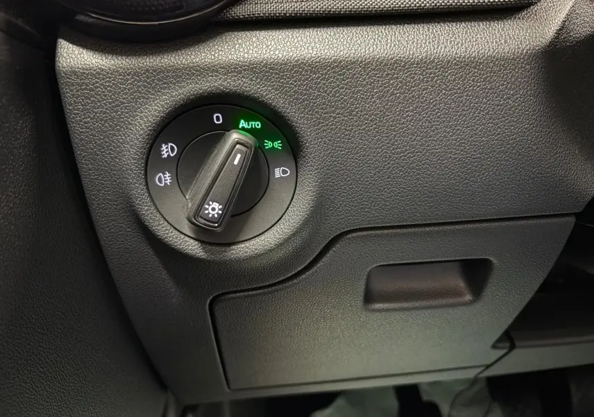 Gros plan sur le bouton de commande des phares avec mode automatique allumé dans l’habitacle de la Skoda Fabia Gris Graphite 2023.