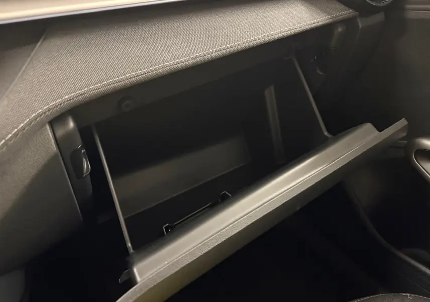 Gros plan sur la boîte à gants ouverte de la Skoda Fabia 2023, intérieur noir avec finition sobre.