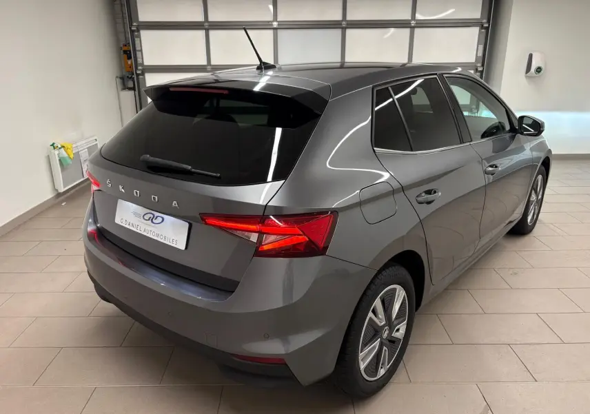 Vue 3/4 arrière droite d'une Skoda Fabia 2023 gris graphite métallisé, avec feux arrière allumés en intérieur.