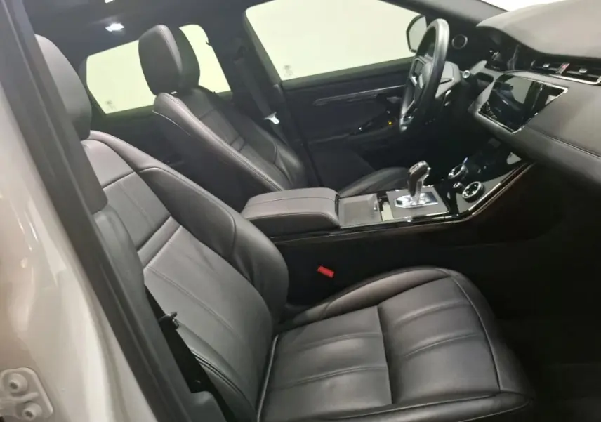 Vue intérieure côté conducteur du Range Rover Evoque 2022, sièges cuir noir et console centrale avec levier de vitesse.