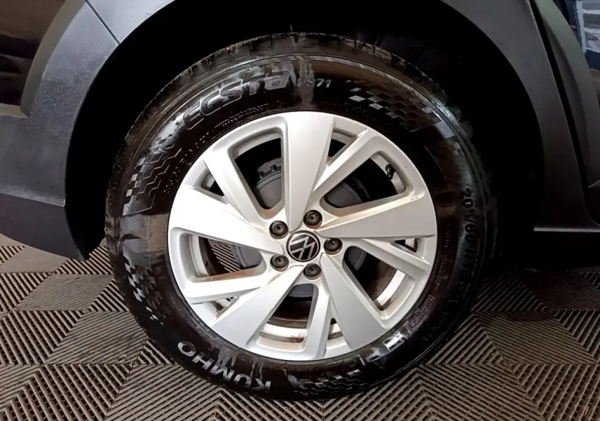 Gros plan sur la roue avant gauche du Volkswagen Taigo noir, mettant en valeur la jante argentée et le pneu Kumho.