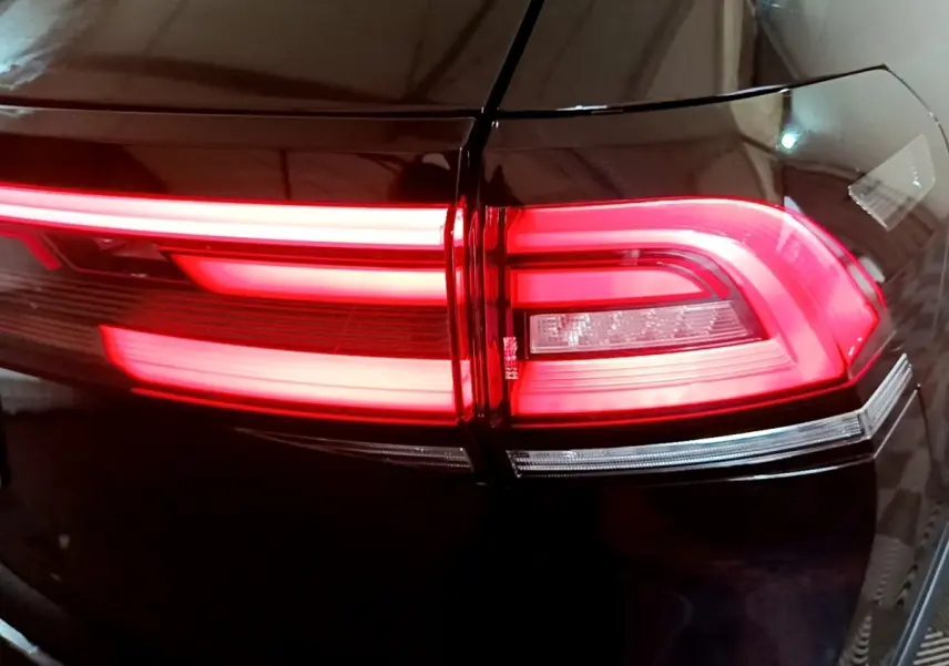 Gros plan sur le feu arrière droit rouge allumé d’un Volkswagen Taigo noir, soulignant ses lignes LED distinctives.