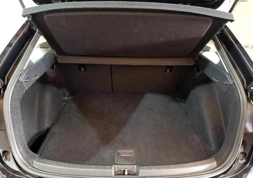 Coffre ouvert vu de l'arrière d'un Volkswagen Taigo noir, montrant l'espace de chargement vide et la tablette de séparation.