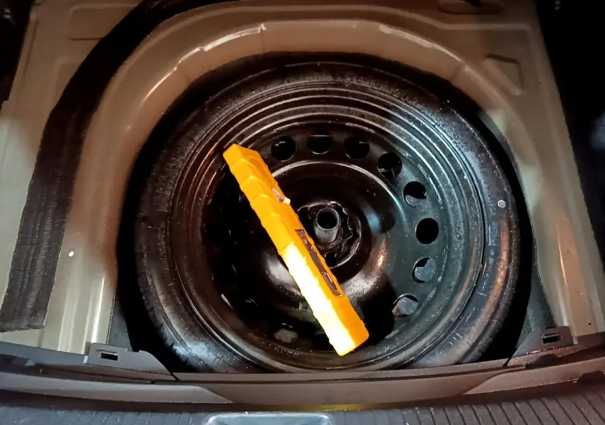 Vue plongeante sur la roue de secours noire dans le coffre d’un Volkswagen Taigo 1.0 TSI 95 Life 2023.