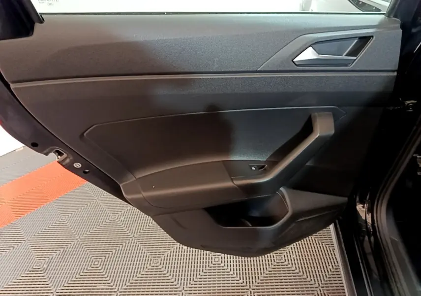 Porte arrière gauche noire de Volkswagen Taigo 2023, intérieur sobre avec poignée angulaire et bouton de lève-vitre.