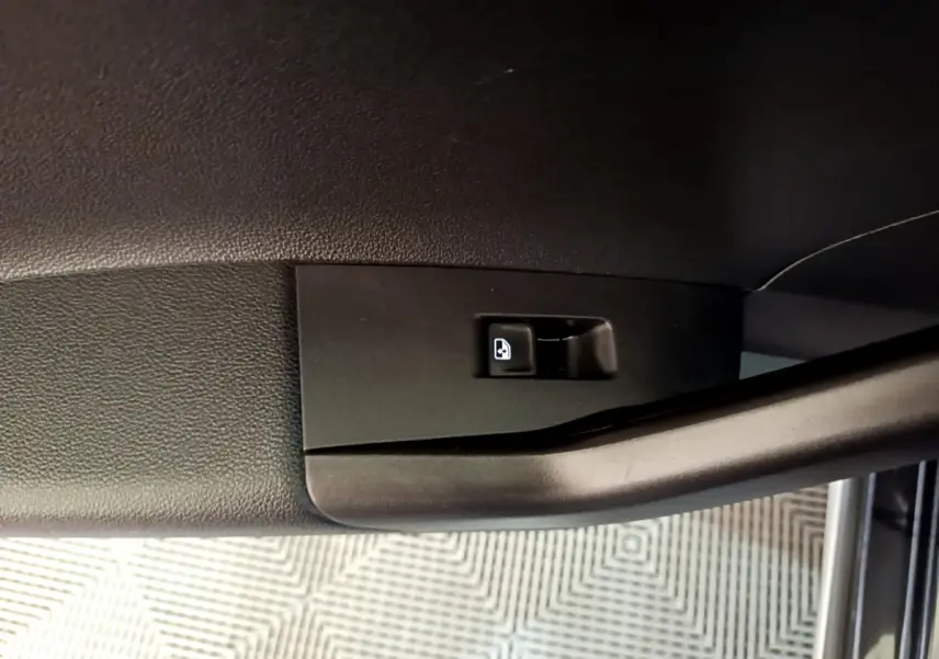 Gros plan sur la poignée intérieure noire de porte côté conducteur du Volkswagen Taigo noir, avec bouton de verrouillage visible.