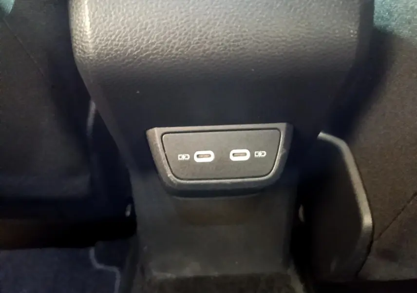Prise USB double type C arrière sous l'accoudoir central d'un Volkswagen Taigo noir, version 2023.