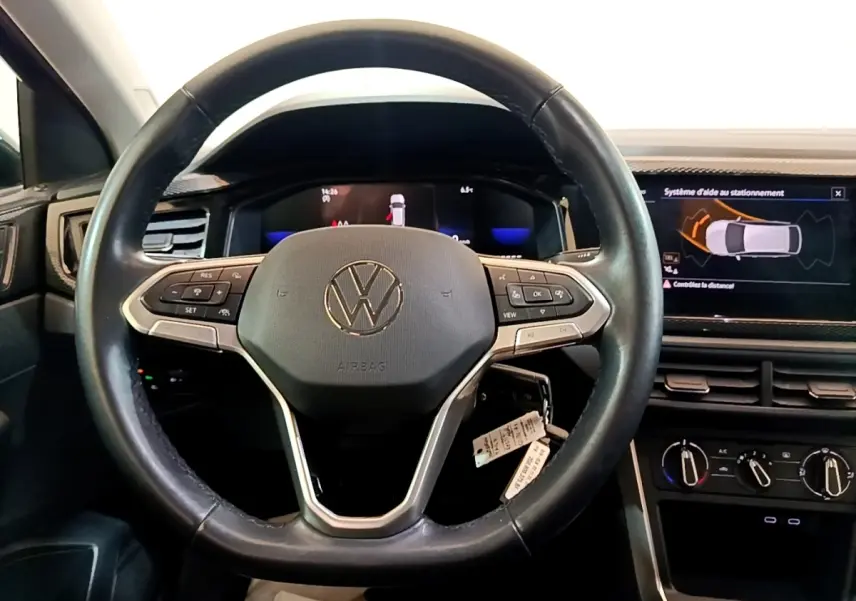 Vue intérieure centrée sur le volant cuir et alu du Volkswagen Taigo 1.0 TSI 95 Life avec écran tactile et affichage digital.