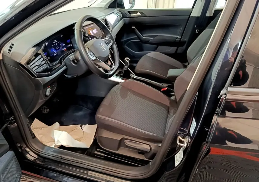 Vue intérieure côté conducteur du Volkswagen Taigo noir 2023, montrant le volant multifonctions et la console centrale.