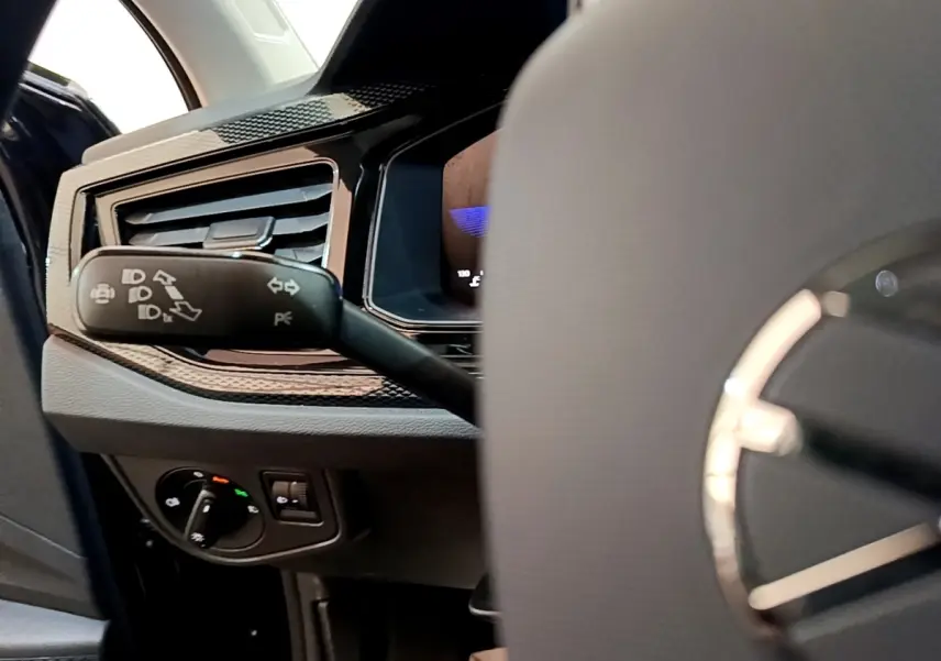 Gros plan sur la commande des clignotants et tableau de bord côté gauche du Volkswagen Taigo noir 2023.