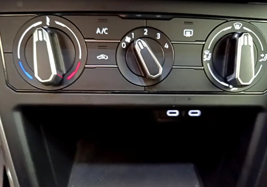 Vue rapprochée des commandes de climatisation noires du Volkswagen Taigo 2023 avec deux ports USB-C éclairés.