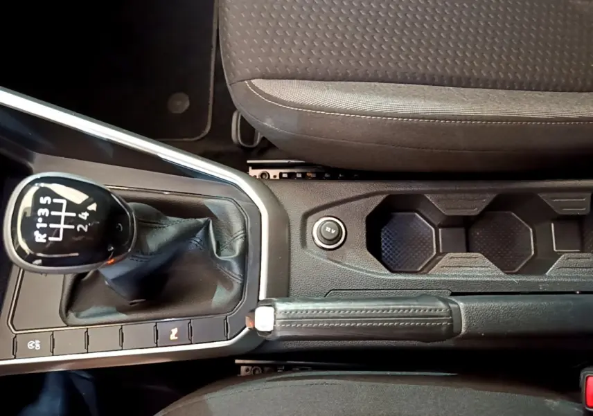 Vue rapprochée de la console centrale du Volkswagen Taigo noir 2023, avec levier de vitesse manuel et frein à main cuir.