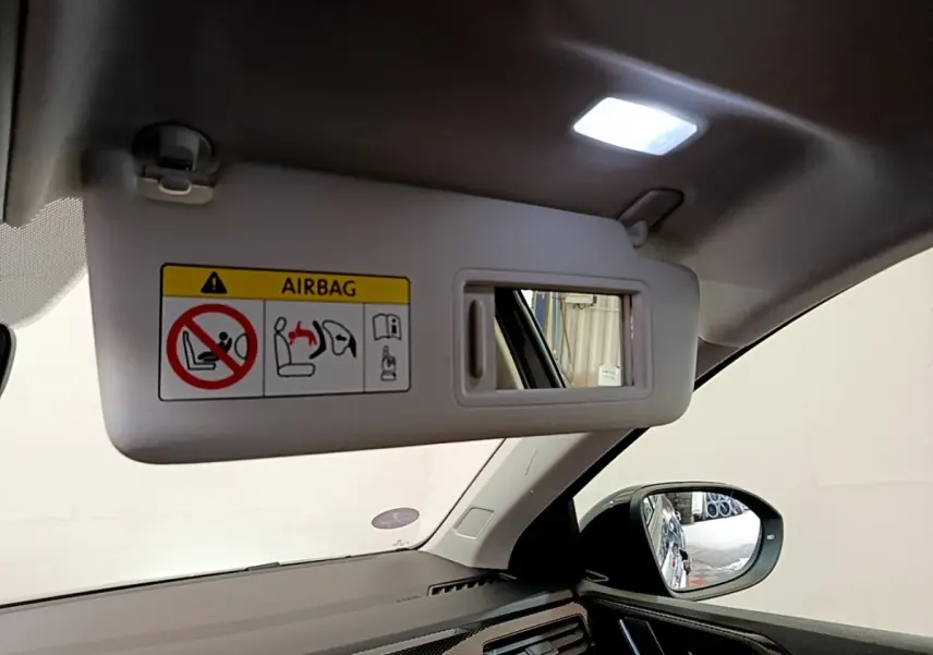 Détail intérieur montrant le pare-soleil côté conducteur avec miroir et rétroviseur extérieur noir du Volkswagen Taigo 2023.
