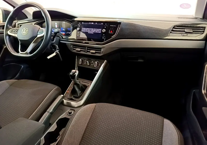 Vue intérieure avant du Volkswagen Taigo 1.0 TSI 95 Life 2023, montrant le volant cuir alu, la boîte manuelle et l’écran tactile central.