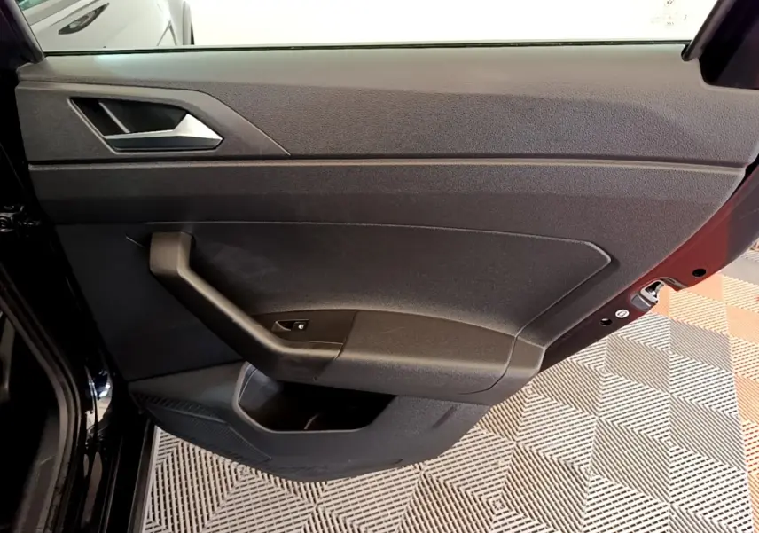 Vue intérieure de la porte arrière gauche noire du Volkswagen Taigo 2023, avec poignée et commande de vitre.