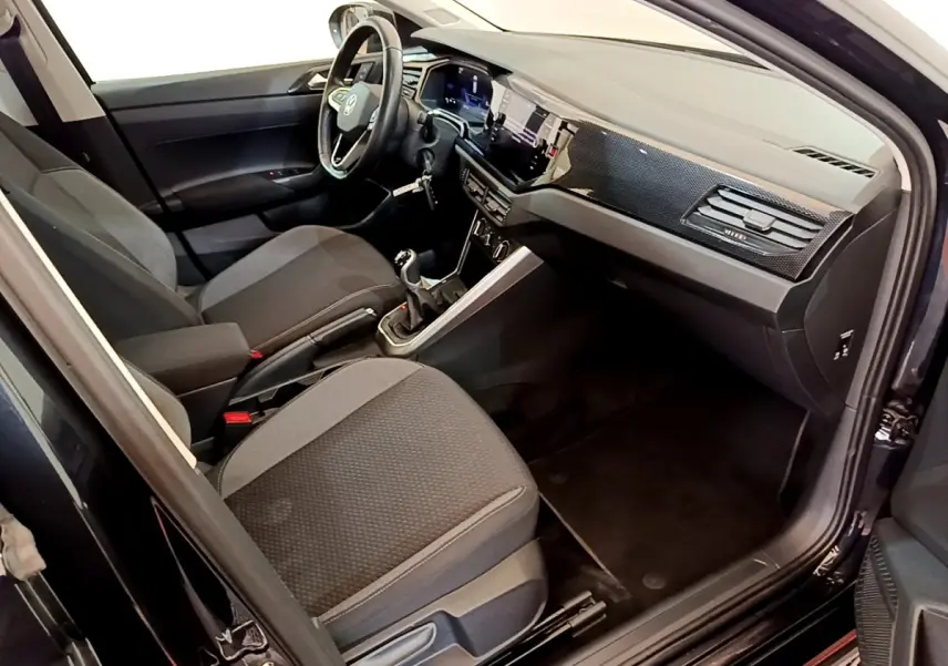 Intérieur avant droit du Volkswagen Taigo noir 2023, avec tableau de bord moderne et boîte manuelle visible.