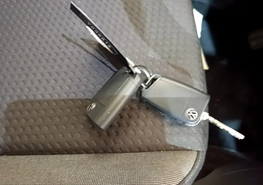 Clé noire Volkswagen Taigo posée sur un siège tissu gris foncé à motifs géométriques.