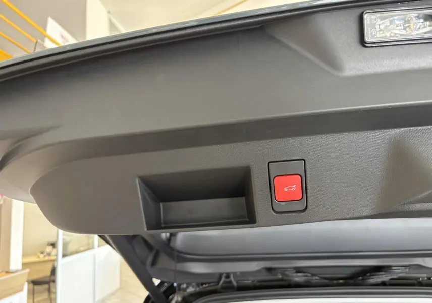 Gros plan sur le bouton de fermeture électrique du hayon du Citroën C5 Aircross vert, intérieur du coffre visible.