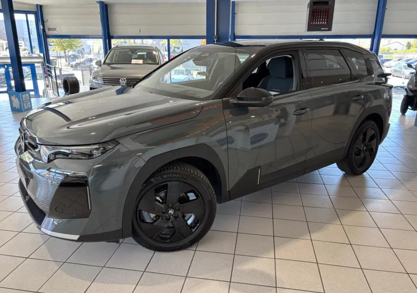 Vue 3/4 avant droite d'un Citroën C5 Aircross vert métallisé avec jantes noires en showroom.