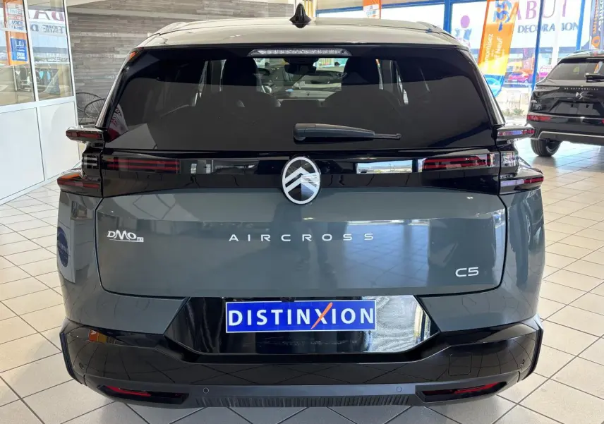 Vue arrière d'un Citroën C5 Aircross vert métallisé avec bandeau noir brillant et feux arrière LED 3D dans un showroom.