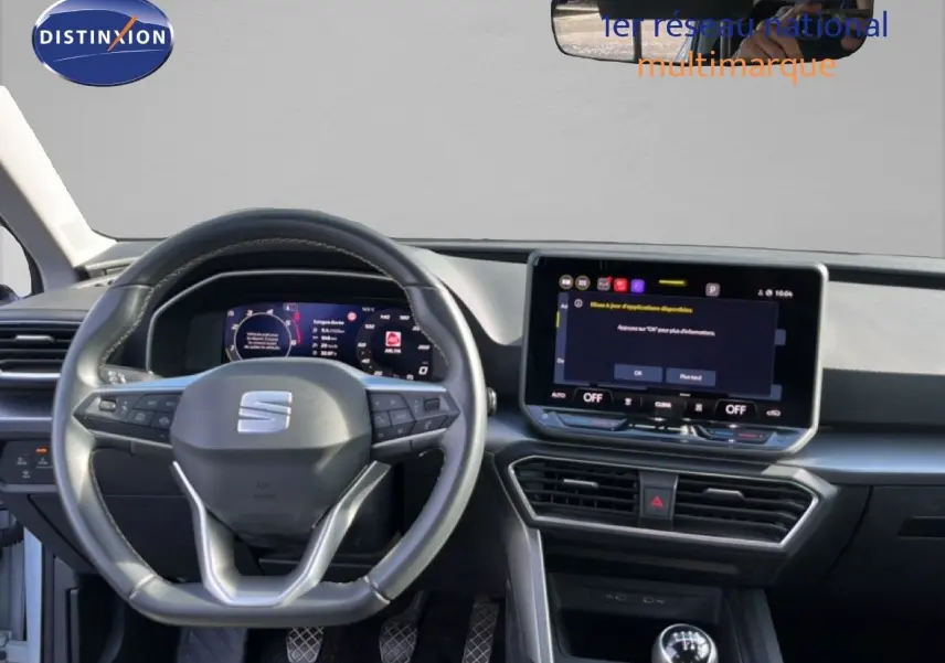 Vue intérieure du tableau de bord du SEAT LEON 2025 blanc neige, avec volant multifonction et écran tactile central.