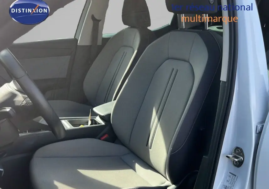 Vue intérieure côté conducteur d’une SEAT LEON 2.0TDI 115CH STYLE XL 2025 avec sièges tissu gris et portière blanche ouverte.