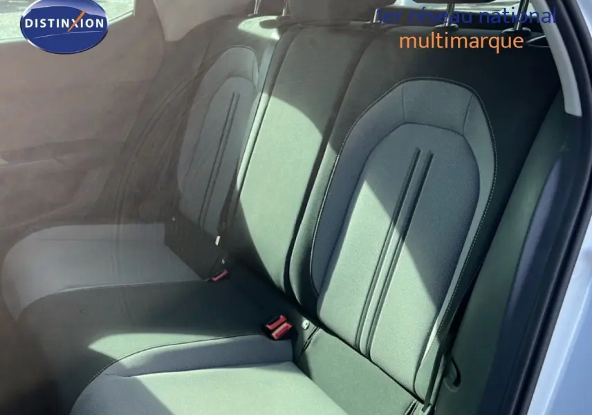 Vue intérieure montrant les sièges arrière en tissu gris noir d'une SEAT LEON blanc neige, porte arrière ouverte.