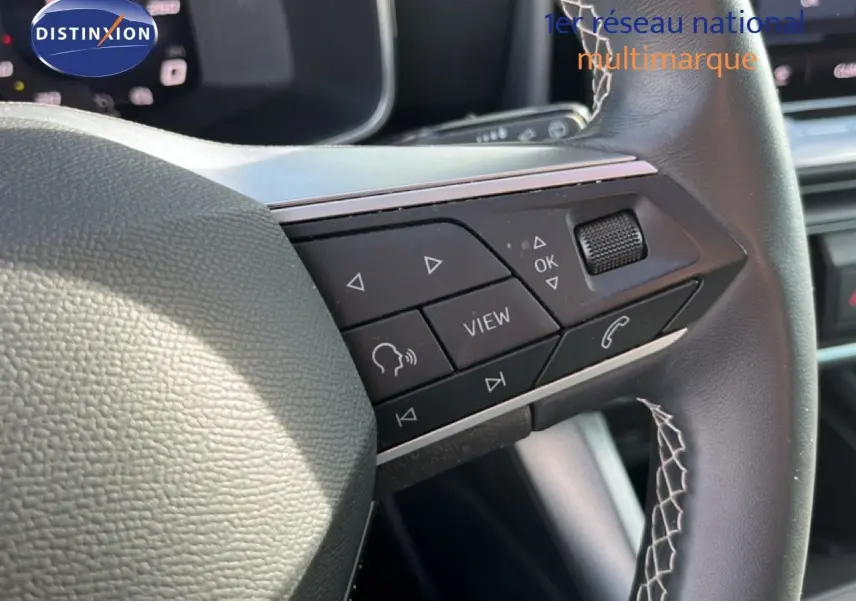 Gros plan sur les commandes multifonctions à droite du volant en cuir noir du SEAT Leon 2025 blanc neige.