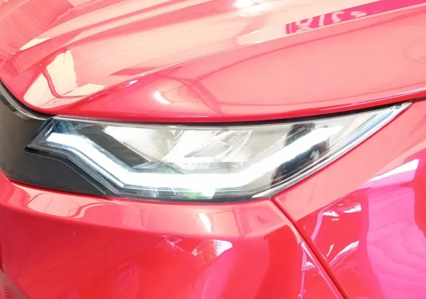 Gros plan sur le phare avant droit d'une Aixam Ambition 0.5 City Pack rouge 2024 avec éclairage LED distinctif.