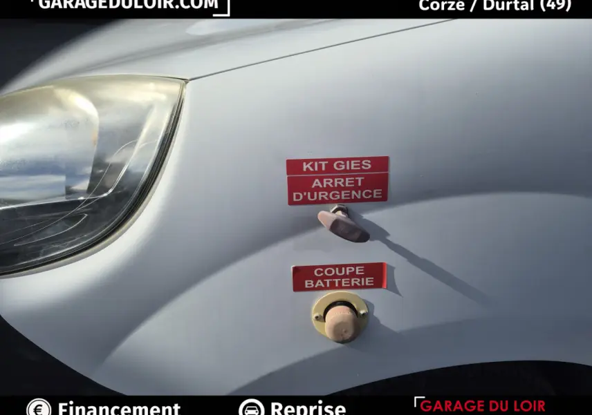 Vue rapprochée de l'aile avant gauche blanche du Renault Kangoo avec interrupteurs d'arrêt d'urgence et coupe batterie.