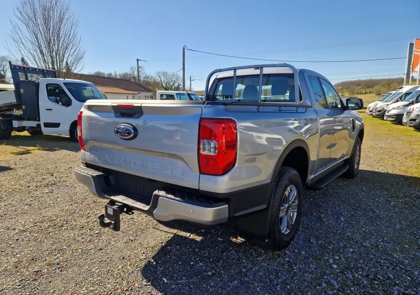 Vue 3/4 arrière droite du Ford Ranger Super Cabine gris iconic avec attelage et barres de protection sur la benne.