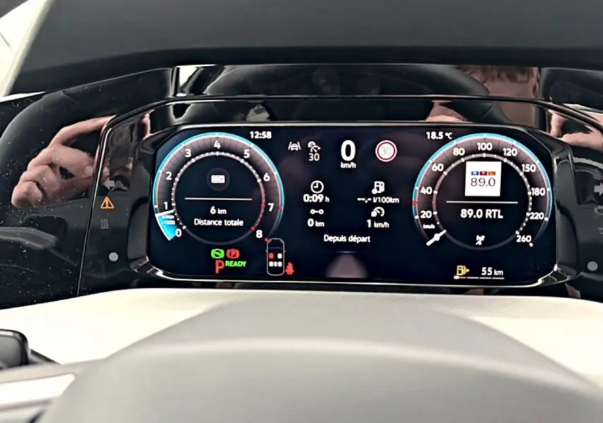 Vue rapprochée du tableau de bord numérique de la Volkswagen Golf noire, affichant la vitesse, la radio et les alertes.
