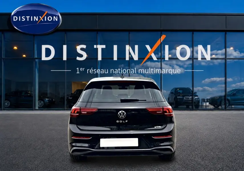 Vue arrière d'une Volkswagen Golf noire 2026 garée devant une vitrine avec logo Distinxion.