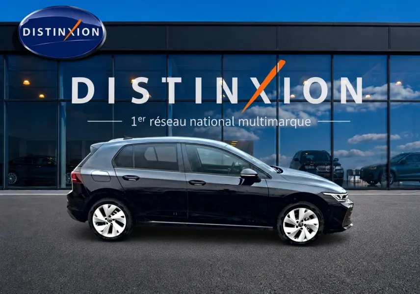 Profil côté gauche d'une Volkswagen Golf noire 2026 garée devant une vitrine avec logo Distinxion.