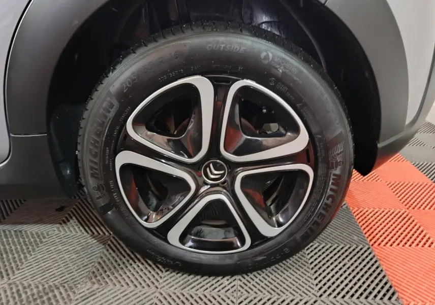 Gros plan sur la roue avant droite d'une Citroën C3 gris clair avec jante alliage noire et argentée.