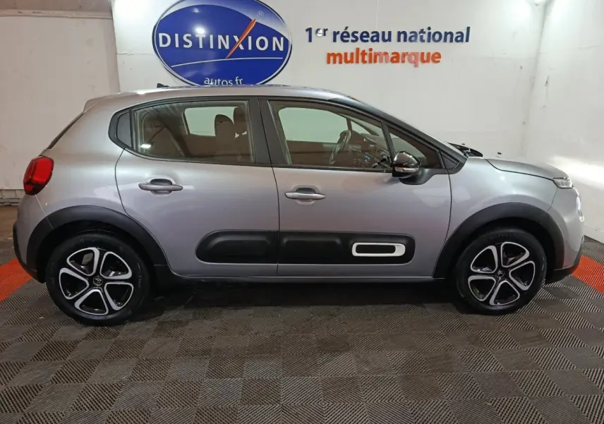 Profil côté droit d'une Citroën C3 gris clair 2024 avec protections noires sur les portières et jantes stylisées.
