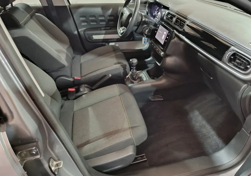 Vue intérieure côté conducteur de la Citroën C3 gris clair 2024, avec sièges tissu, volant multifonctions et écran tactile central.