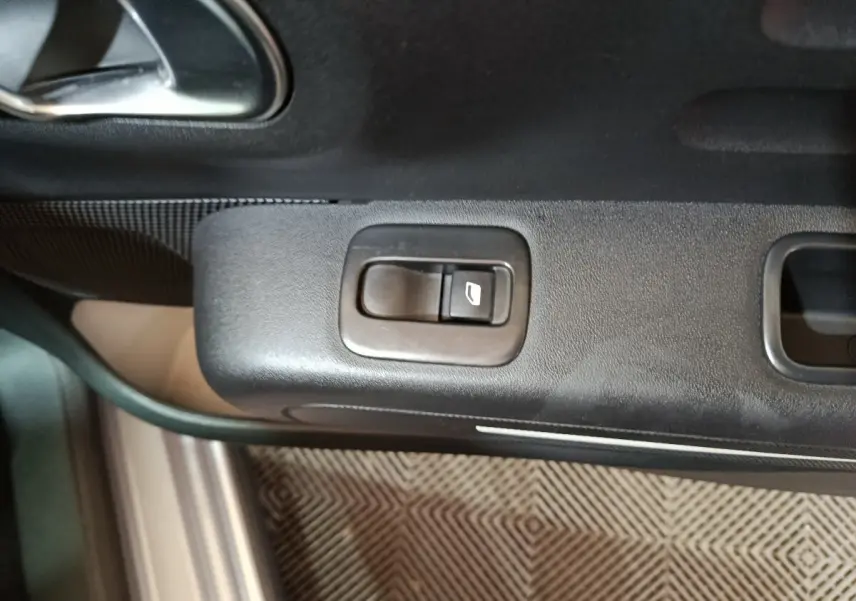 Gros plan sur la commande de lève-vitre côté conducteur de la Citroën C3 gris clair, intérieur noir.