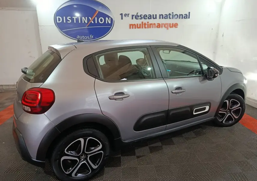 Citroën C3 gris clair vue de profil droit en intérieur, avec protections latérales noires et jantes distinctives.