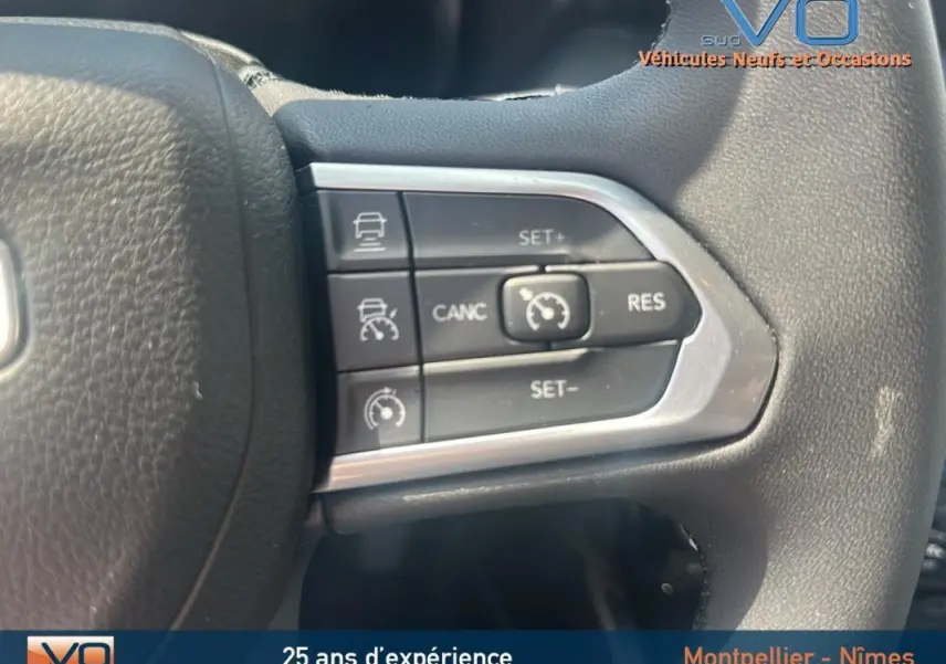 Gros plan sur les commandes de régulateur de vitesse au volant noir du Jeep Compass blanc 2024 e-Hybrid Altitude