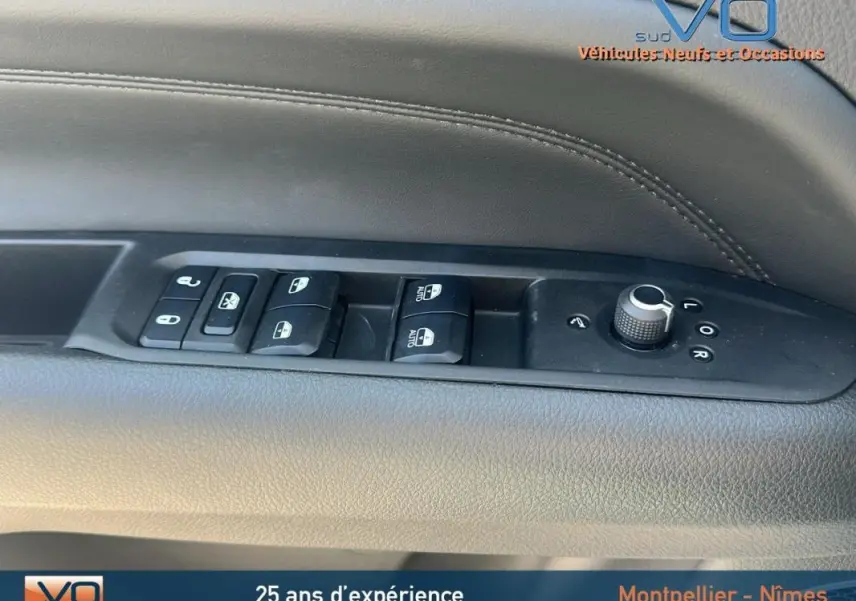 Gros plan sur la commande des vitres et rétroviseurs côté conducteur du Jeep Compass blanc 2024 avec pack hiver.