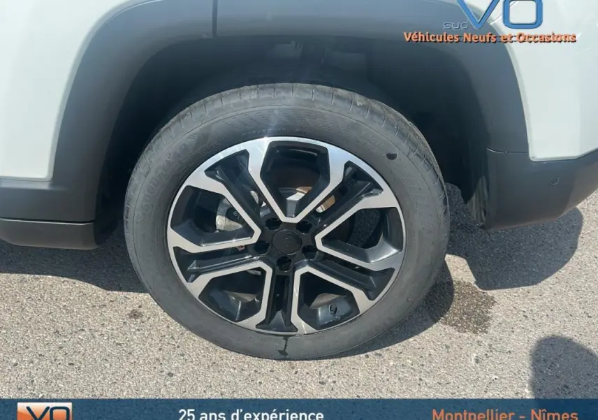 Gros plan sur la jante 17 pouces noire et argent du côté gauche d'un Jeep Compass blanc 2024 avec roue de secours visible.