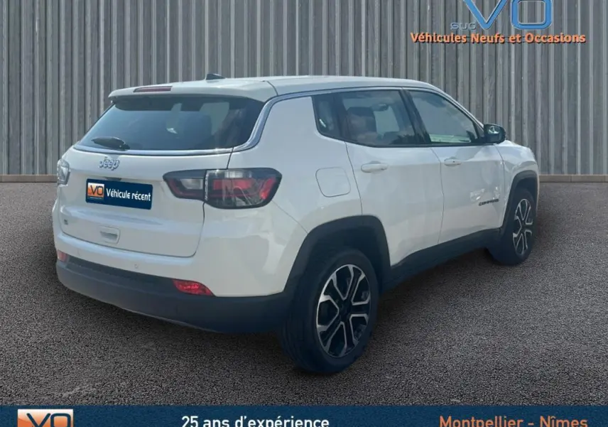Vue 3/4 arrière droite d'un Jeep Compass blanc 2024 avec jantes 17 pouces et roue de secours visible sur le hayon.